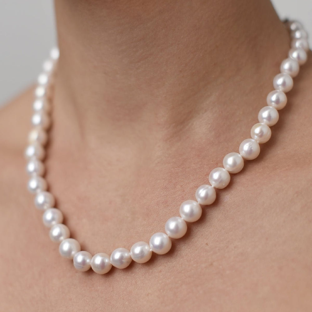 Choker with 10mm round pearl on a person's neck, featuring white pearls strung on a rhodium-plated silver chain, 40+5 cm in length.