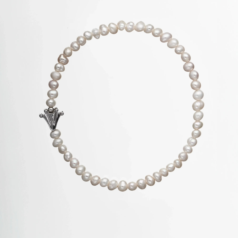 Bracelet with small white pearls and a frog's paw charm