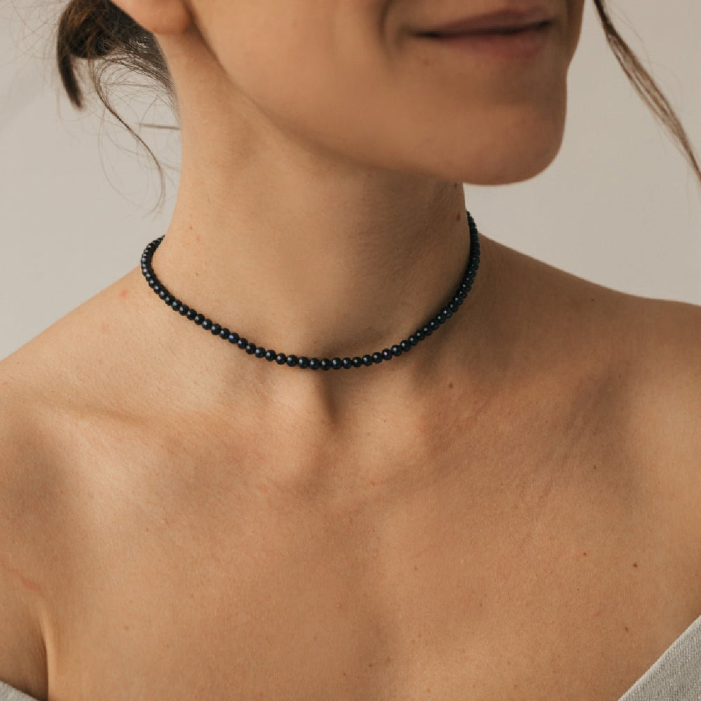 Woman wearing a minimalist choker with a 4mm round black pearl made of high-quality silver.