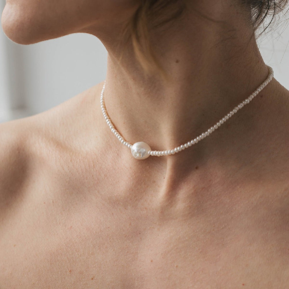 
                      
                        Choker with white pearl and baroque pearl 10 mm silver on a woman's neck displaying its elegant design and rhodium plated silver.
                      
                    