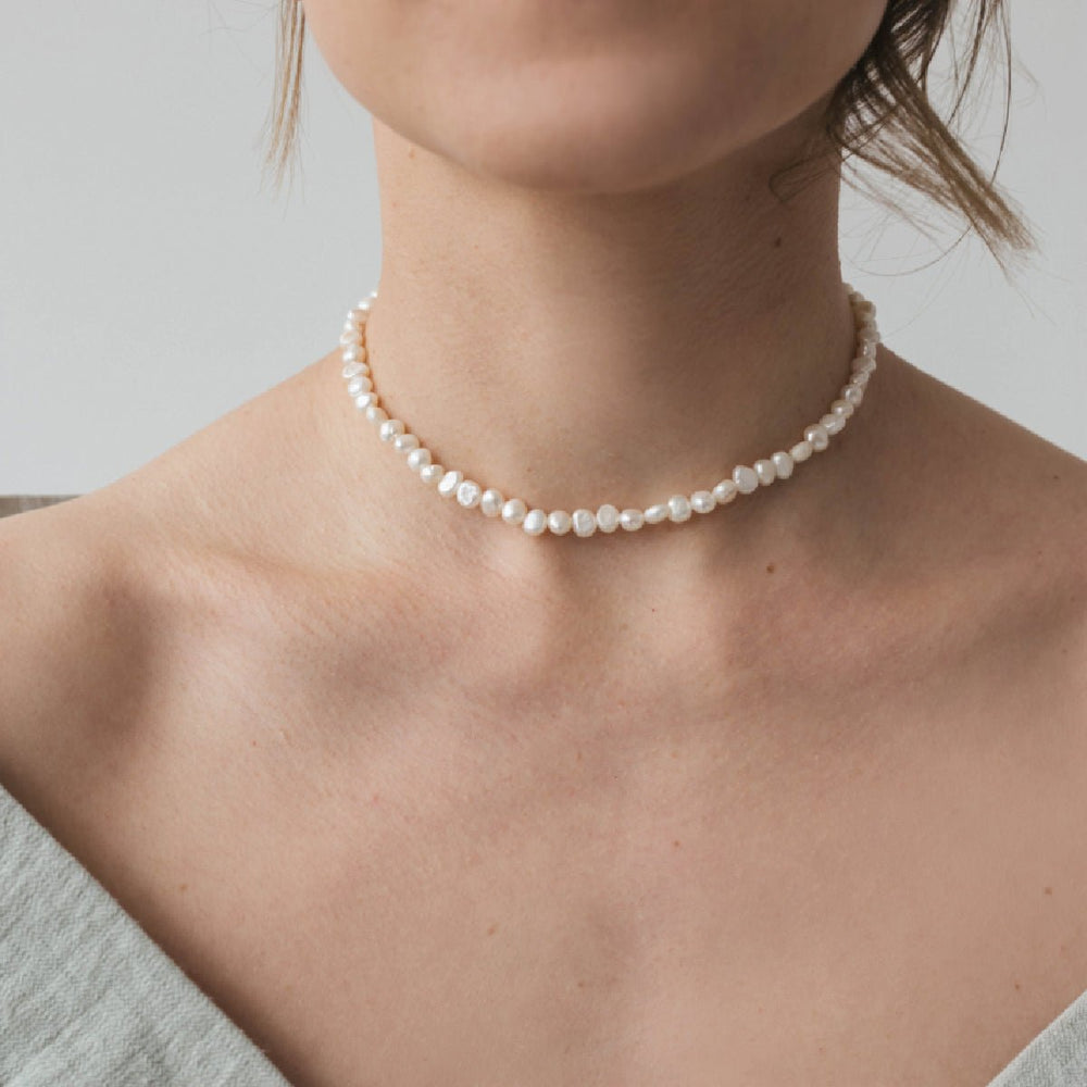 
                      
                        A woman wearing a choker with a 5 mm baroque white pearl on a rhodium plated silver chain.
                      
                    