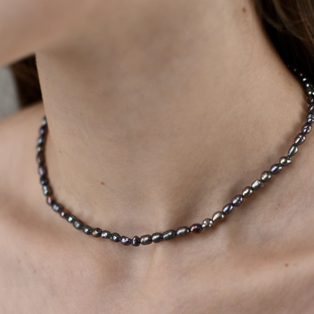 Choker with 4 mm black baroque pearl in rhodium-plated silver worn around the neck.