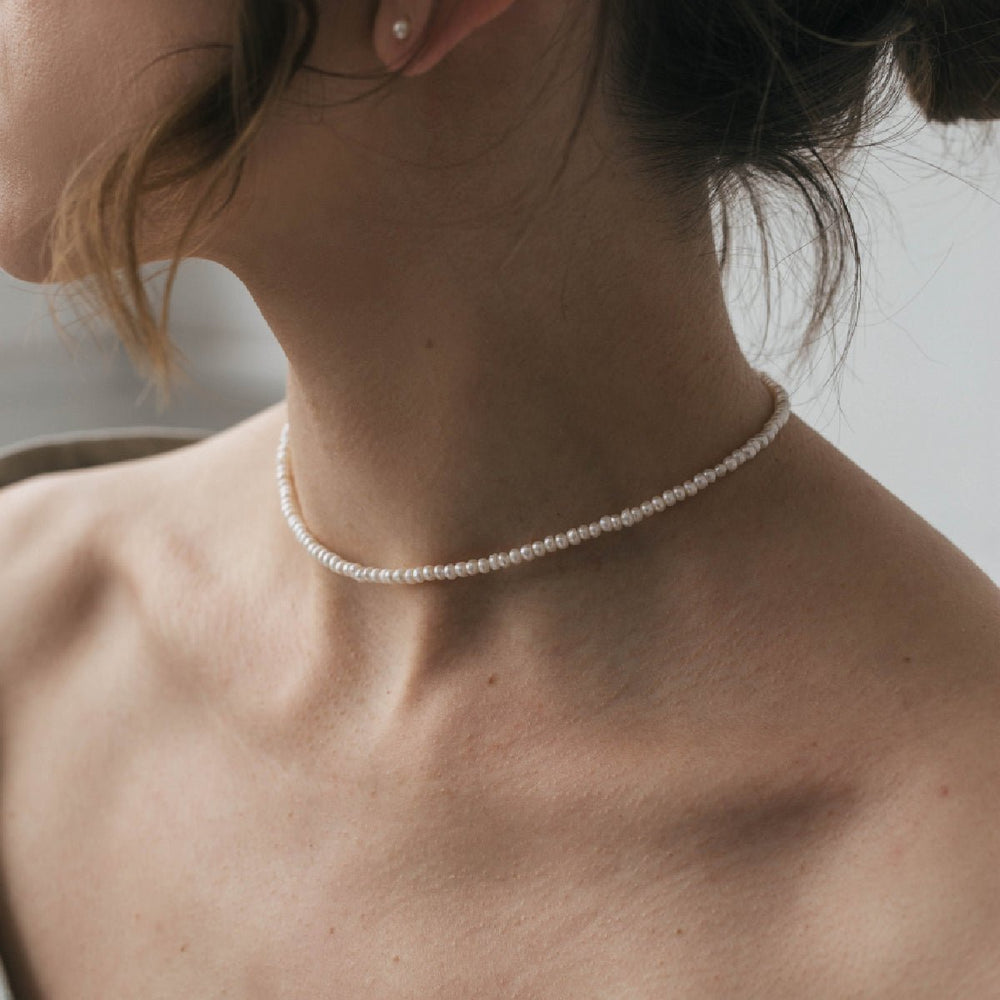 
                      
                        Choker with white round pearl 3 mm silver around a woman's neck.
                      
                    