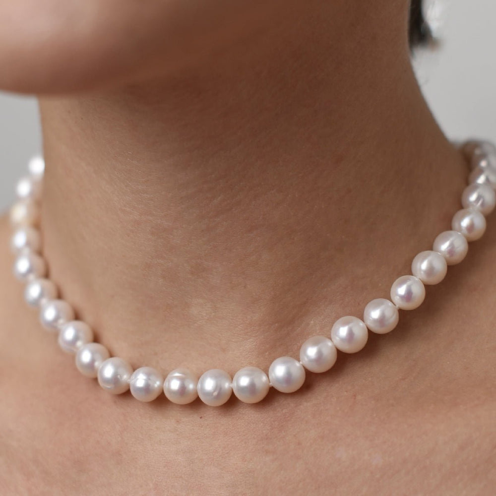 Choker with 10mm round pearl in rhodium-plated silver on a person's neck.