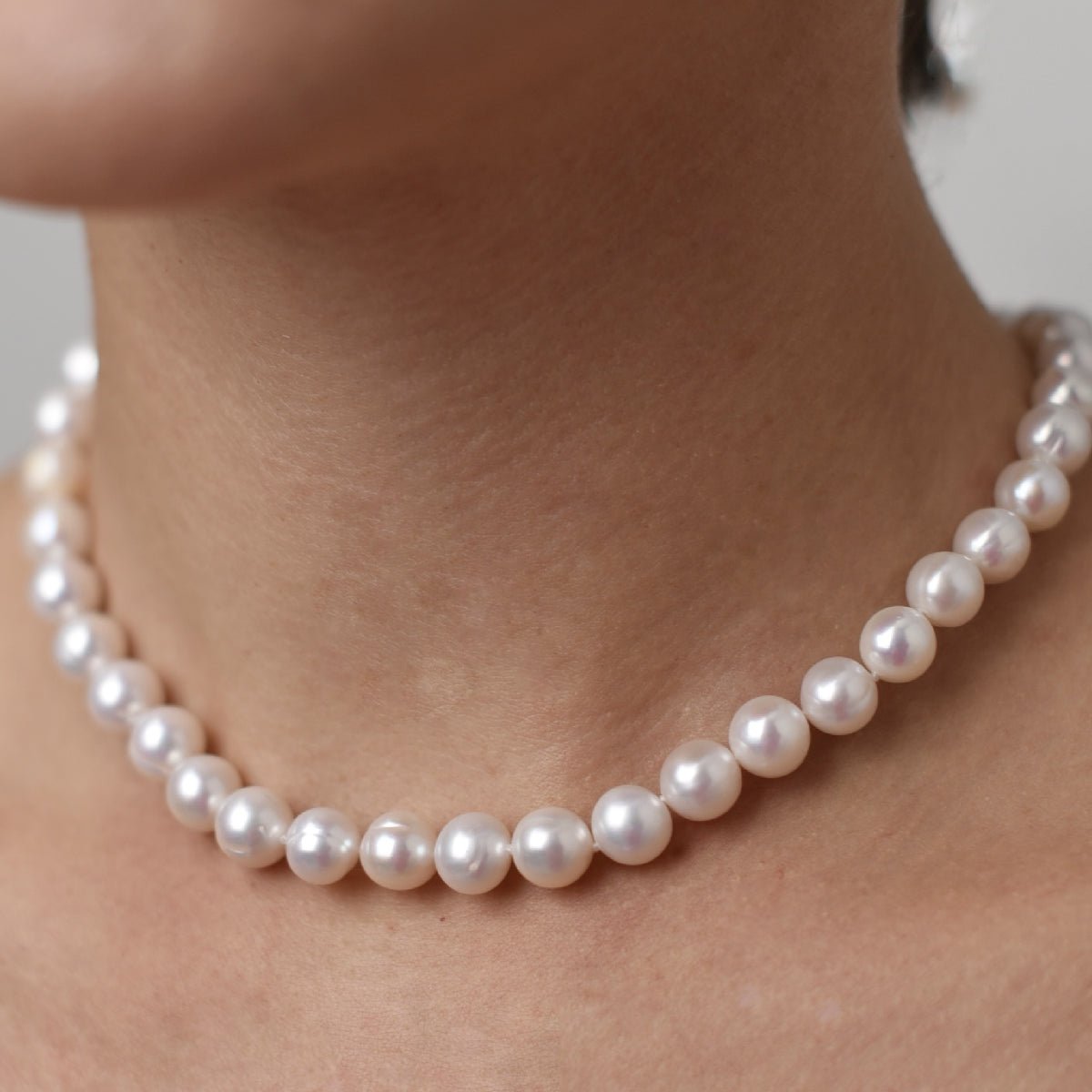 Choker with 10mm round pearl in rhodium-plated silver on a person's neck.