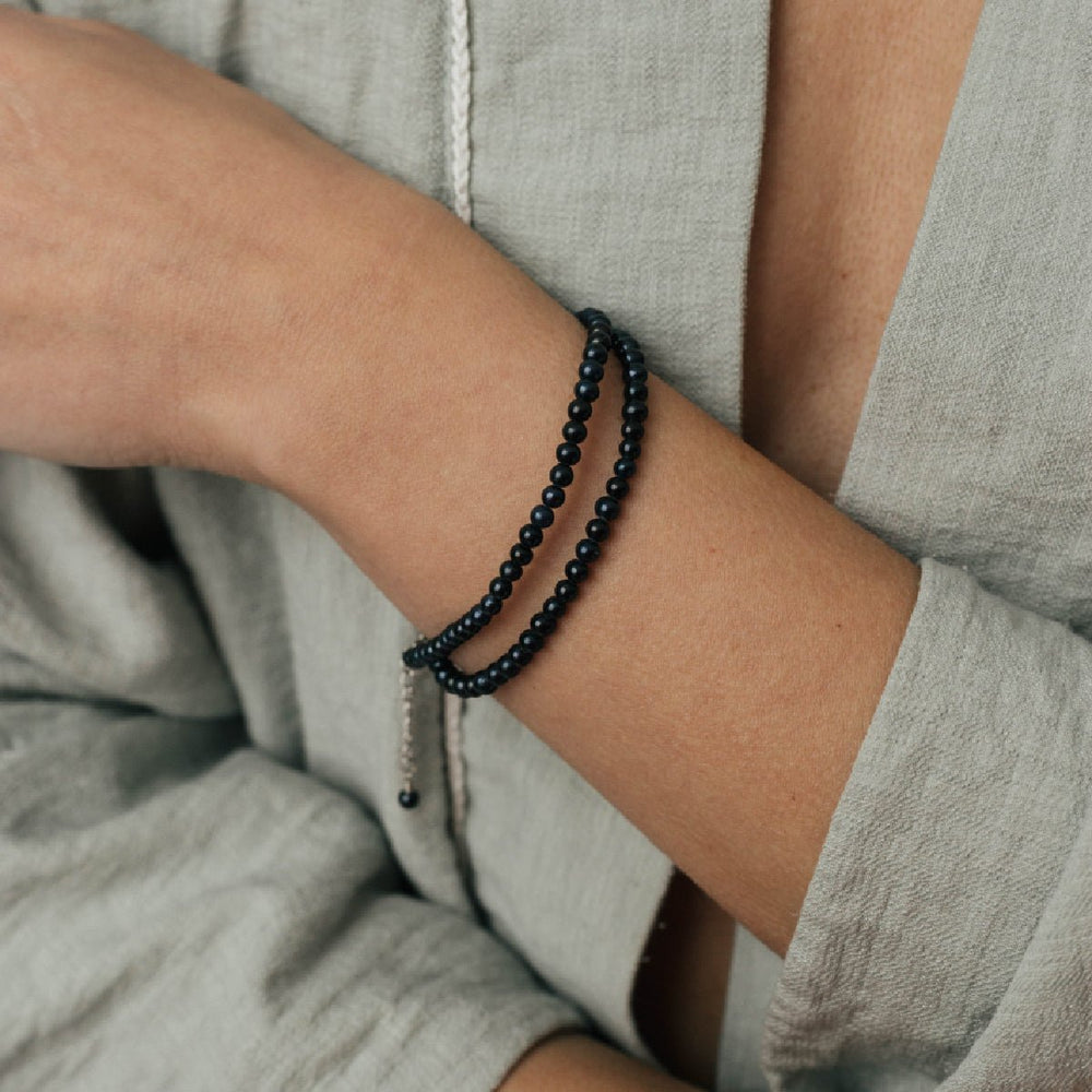 
                      
                        Minimalist choker with 4mm round black pearl worn as a wristlet, made with silver metal on a person's wrist.
                      
                    